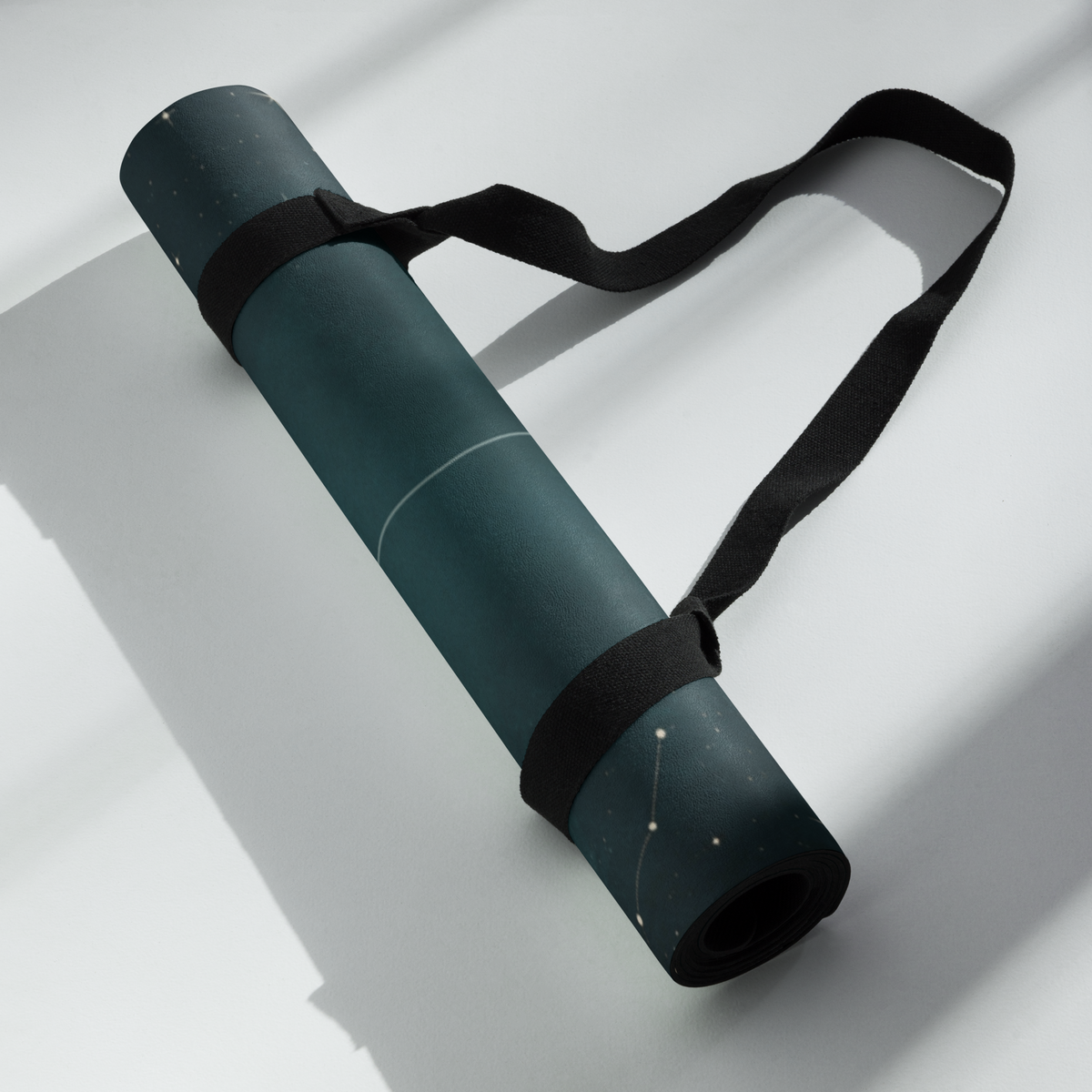 Best Yoga Mat For Hot Yoga rolled up with a strap, featuring teal lunar phases design against a light background.