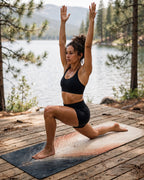 Woman practicing yoga on Hot Yoga Mat | Desert Core by MIYRA, with arms raised, outdoors by a lake.