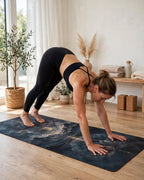 Woman performing downward dog on Hot Yoga Mat | Midnight Lotus in a bright yoga studio.