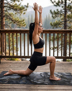 Woman practicing a lunge pose on a Hot Yoga Mat | Onyx Flow with a beautiful, nature background.