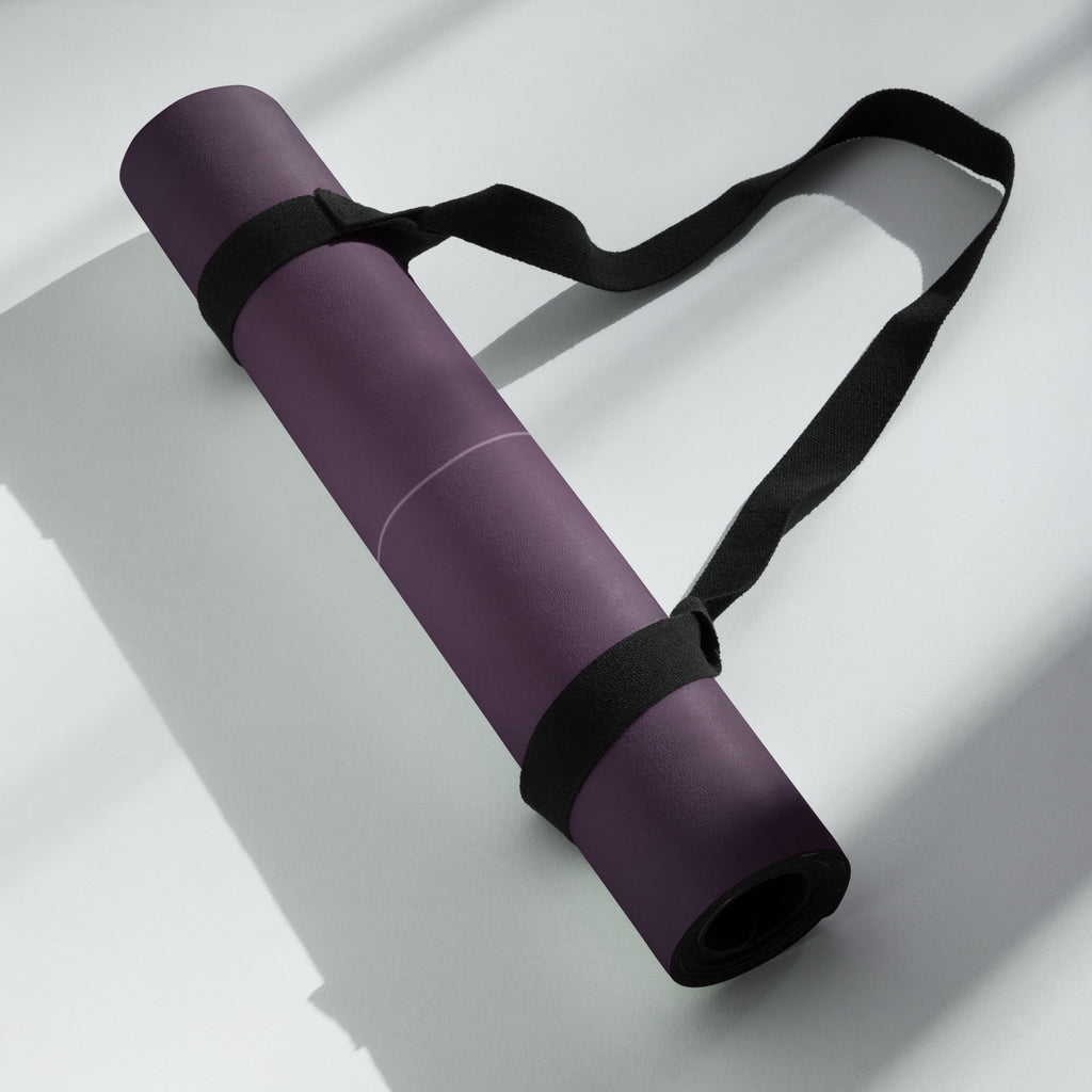 Best Yoga Mat For Hot Yoga - Plum Wisteria yoga mat rolled up with strap on a light surface.