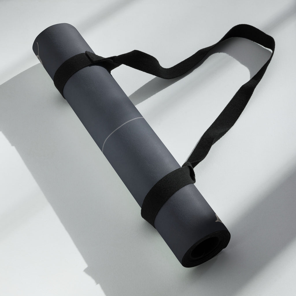 Rolled charcoal yoga mat with carrying strap, perfect for the best yoga mat for hot yoga, offering stability and comfort.